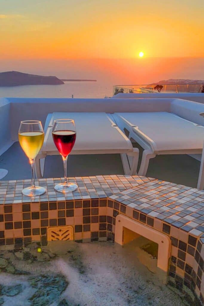 Two wine glasses on the edge of a hot tub at sunset on Santorini Greece